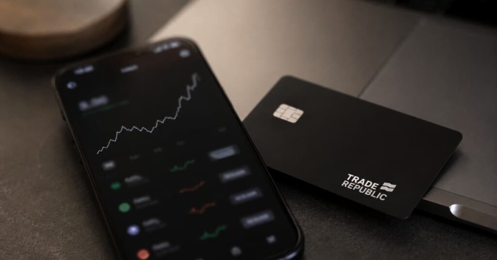 App de Trade Republic en un móvil junto a una tarjeta bancaria.