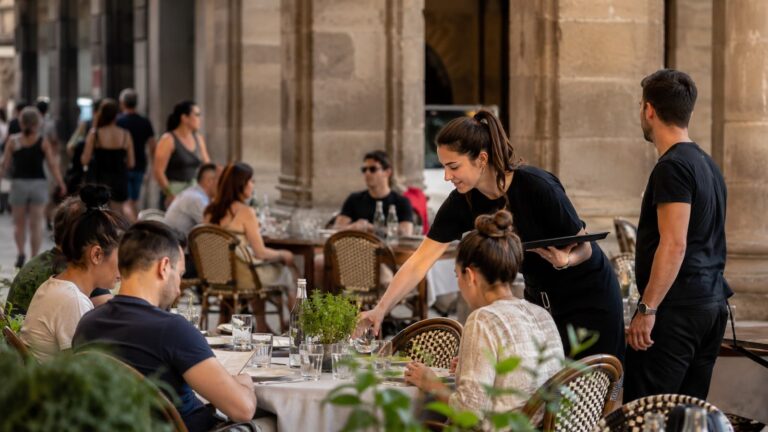Camareros atienden una terraza en Cataluña símbolo del debate entre mejores condiciones laborales productividad y precios en la hostelería