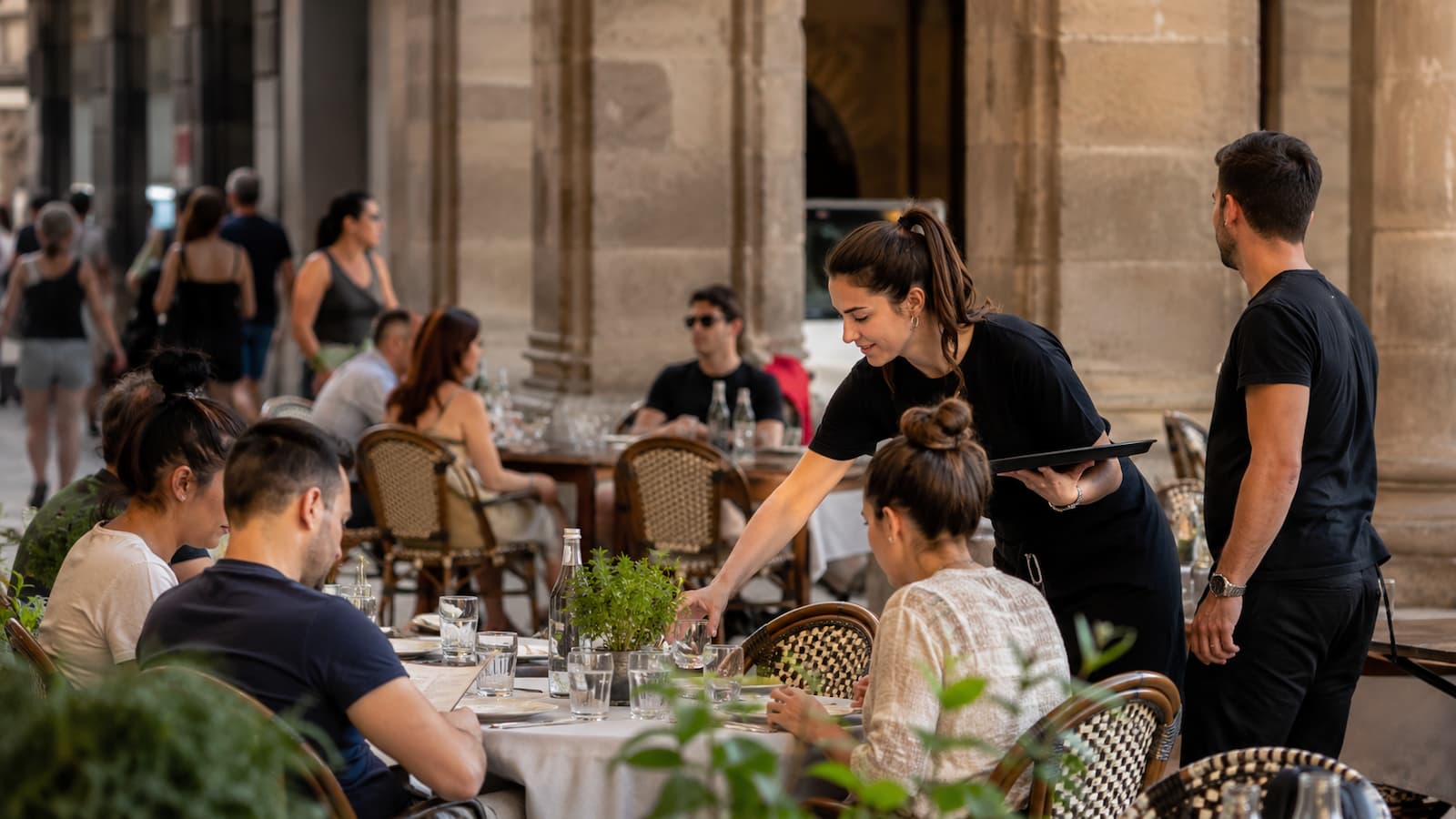 Camareros atienden una terraza en Cataluña símbolo del debate entre mejores condiciones laborales productividad y precios en la hostelería