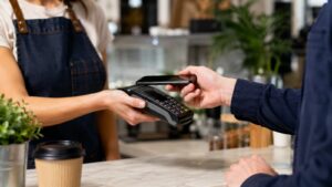 Comercio cobrando con móvil y datáfono en mostrador